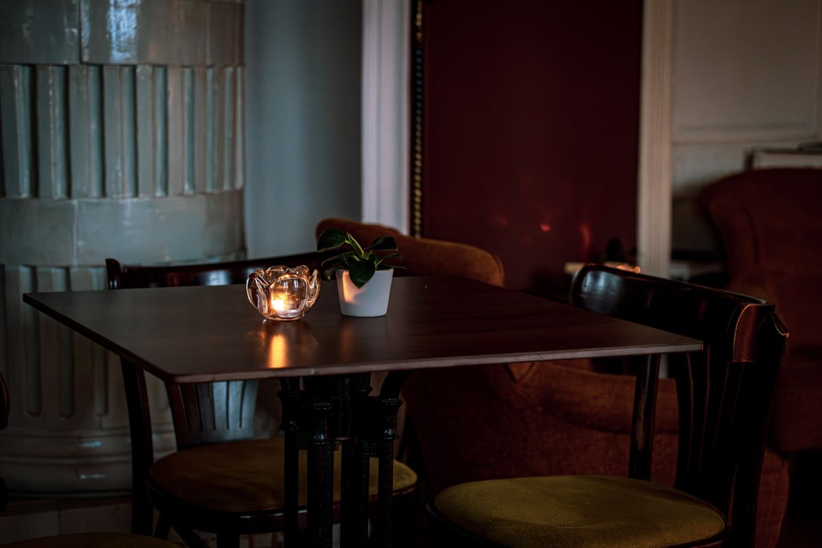 Detail stolu se zářící svíčkou a rostlinou v útulné restauraci